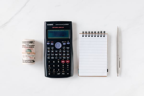 a roll of money, calculator, and notepad