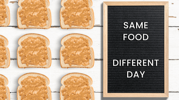 A letter board sign that says, same food different day. There are pieces of bread with peanut butter on them lined up next to the sign.