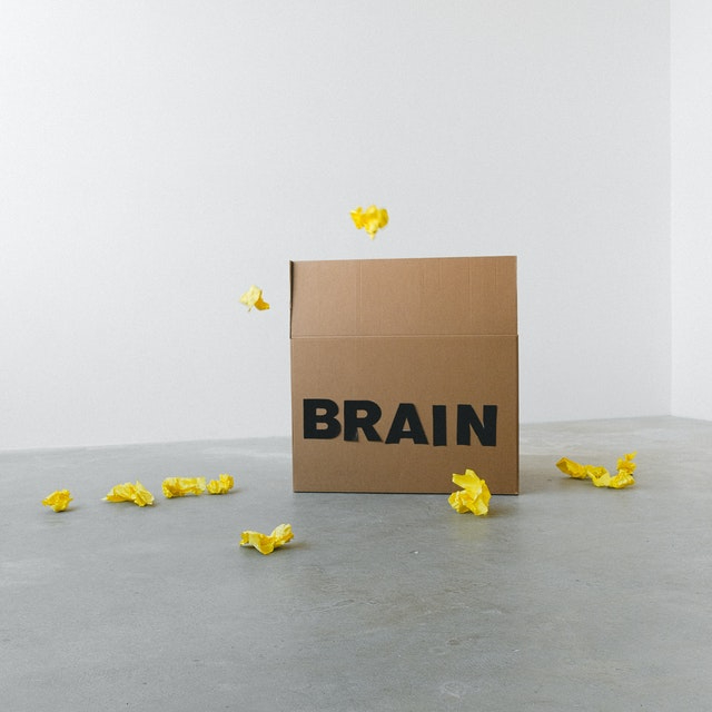 a cardboard box labeled "brain" with crumpled yellow papers thrown around it