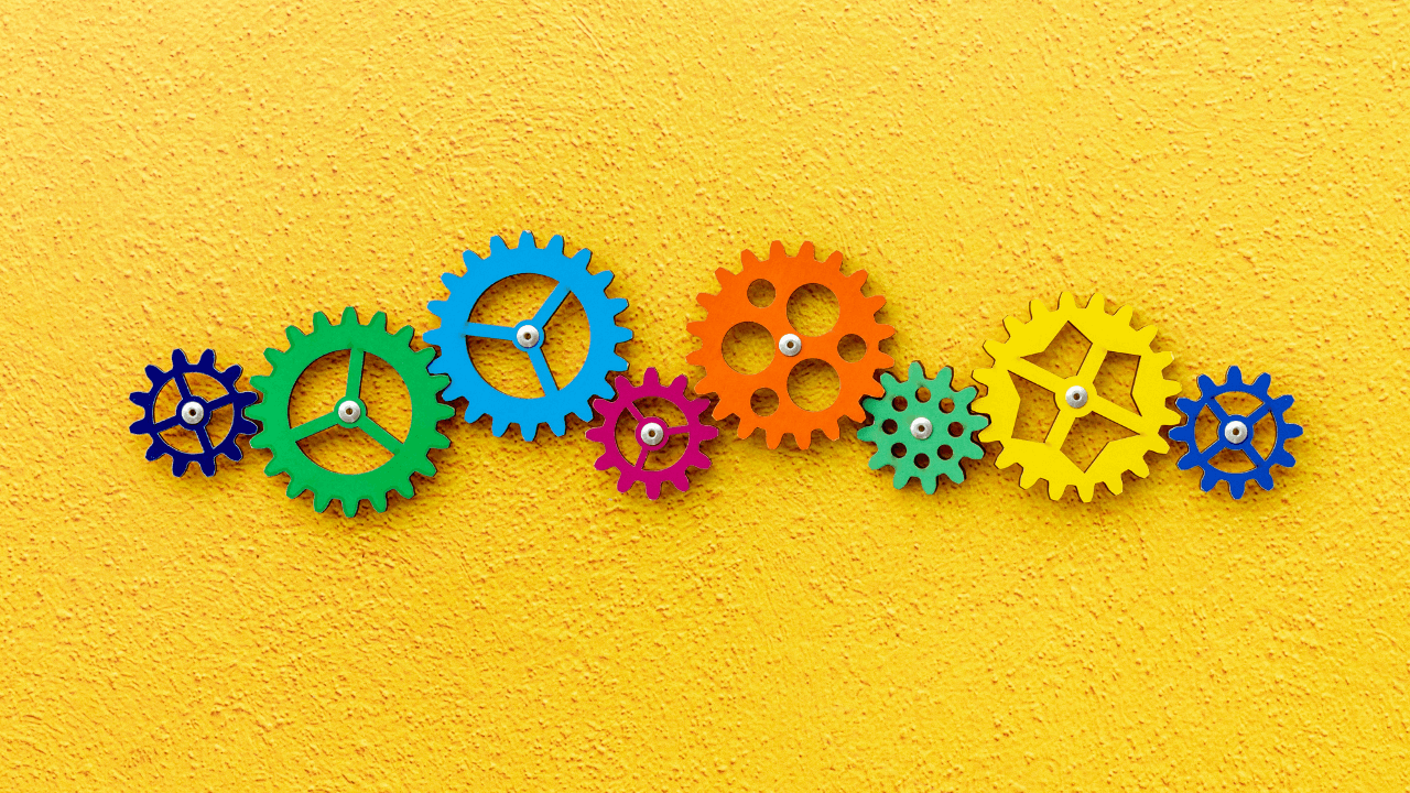 Bright yellow background with different colored gears lined up in the middle