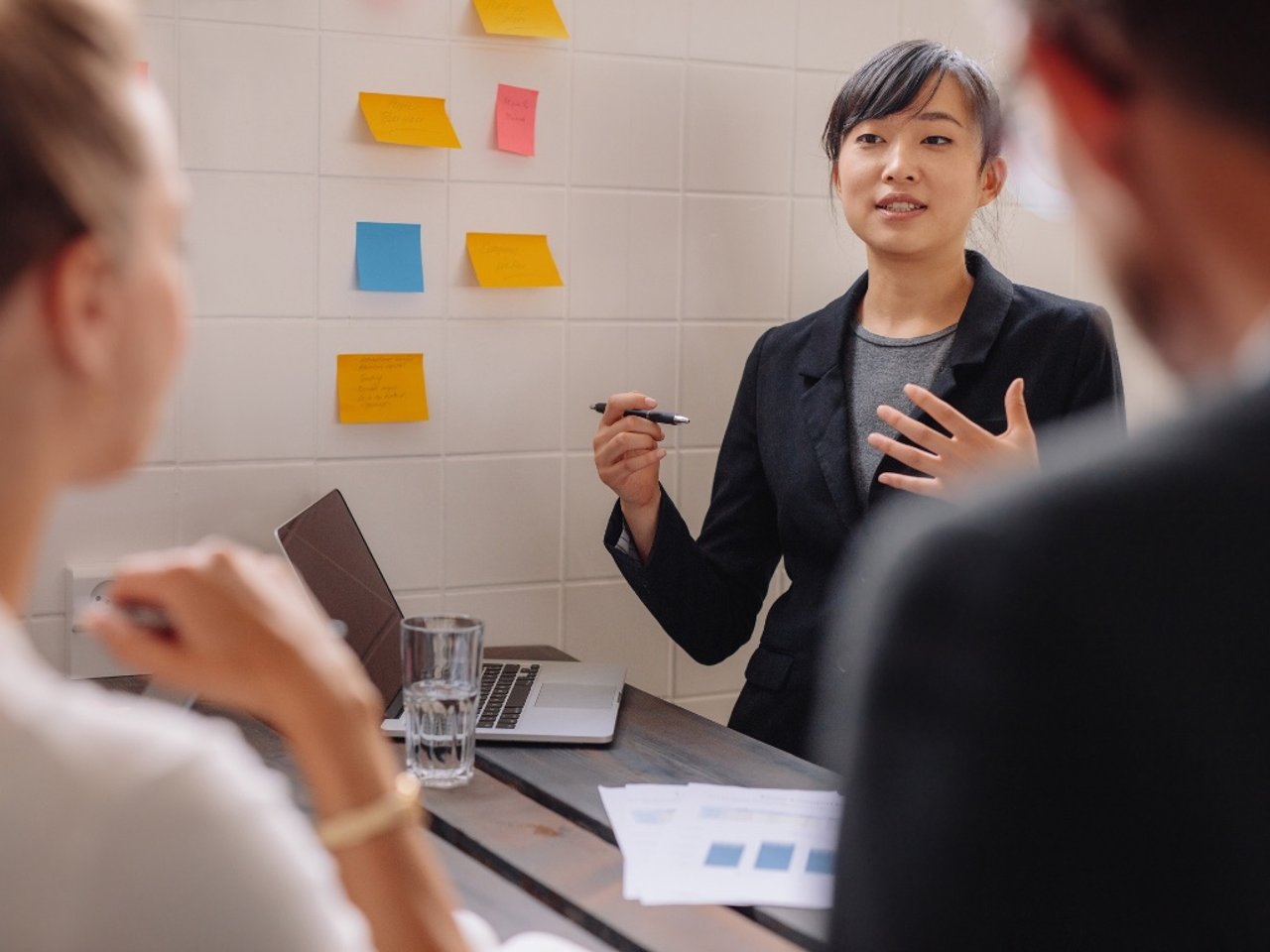 Woman in a suit supporting her argument in front of two colleagues