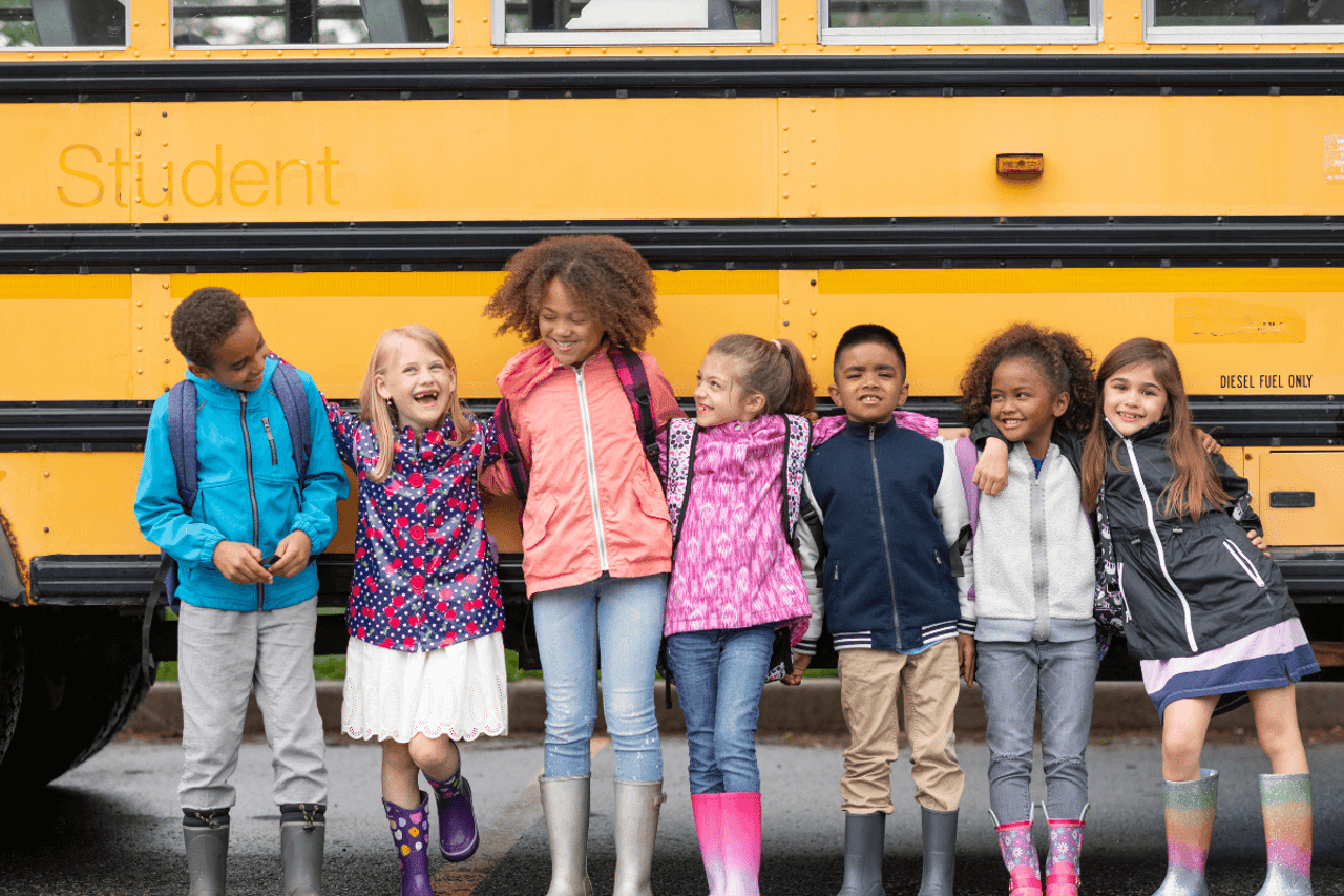 seven school-aged kids lined up in front of a school bus; some of them have ADHD, but which ones?