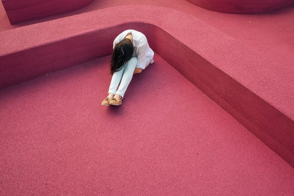 woman sitting on a red carpet, putting her head between her knees.