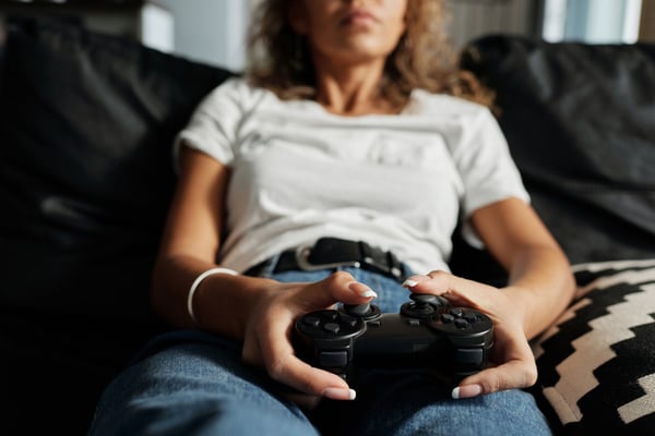 Photo of a woman leaning back in a sofa, holding a video game controller in her hands