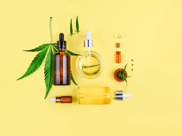 yellow background; marijuana/cannabis/pot/weed leaf with a variety of oils and other CBD products