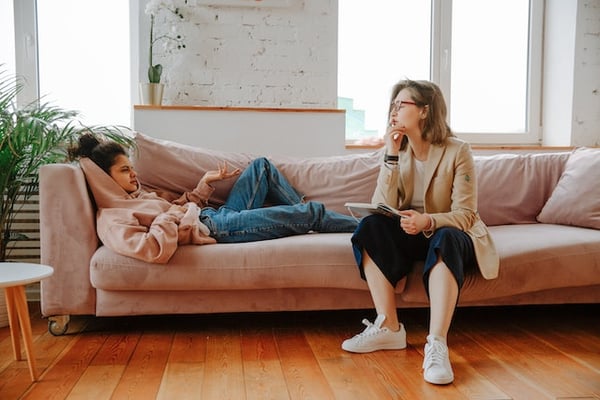 two women on a couch. one is lying down and talking about her adhd challenges while the therapist is listening closely