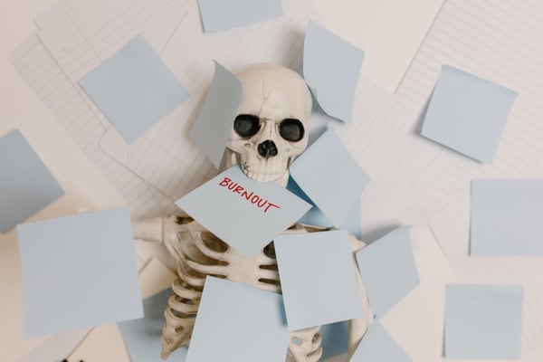 a skeleton with a piece of paper in its mouth that says "burnout"