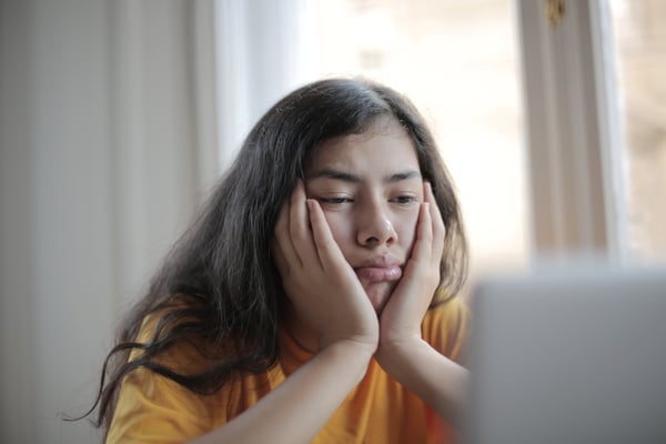 kid sitting in front of a computer with a frown on her face