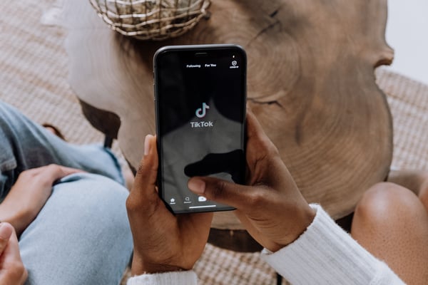 a woman's hand holding a phone with TikTok on the screen