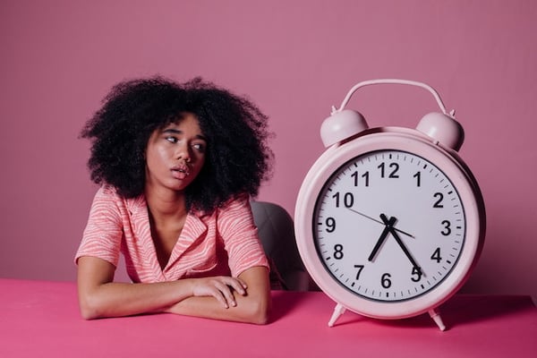 a woman sitting next to a large alarm clock