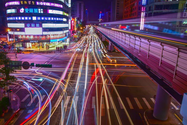 Blurry traffic lines going in all directions in an Asian city at night. Photo by Pixabay.