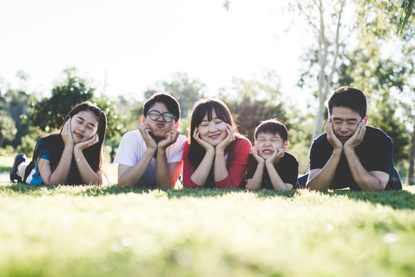 An Asian family of five posing for a photo in the grass