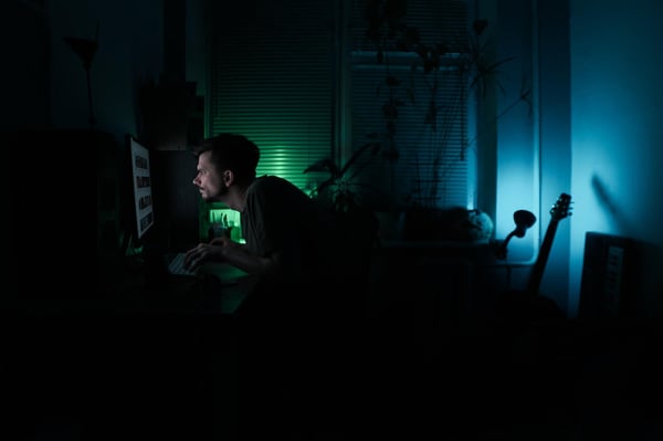 Hyperfocus and sleep deprivation are among the top reasons why people with ADHD neglect their basic human needs and functions. Photo of a man on his computer late at night.