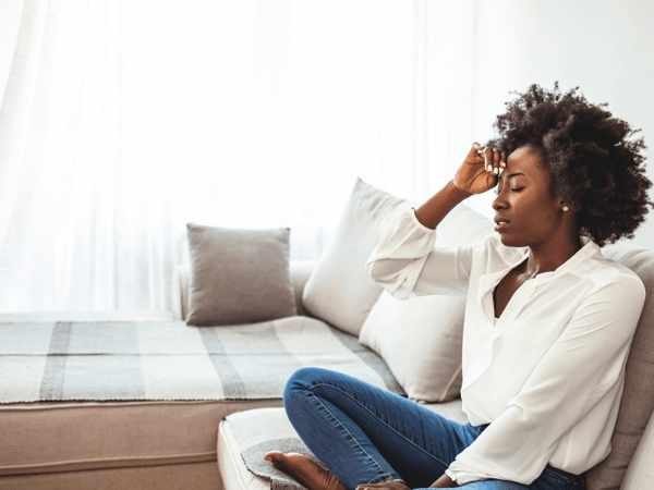 A woman with ADHD and bruxism is sitting on her bed with a headache.