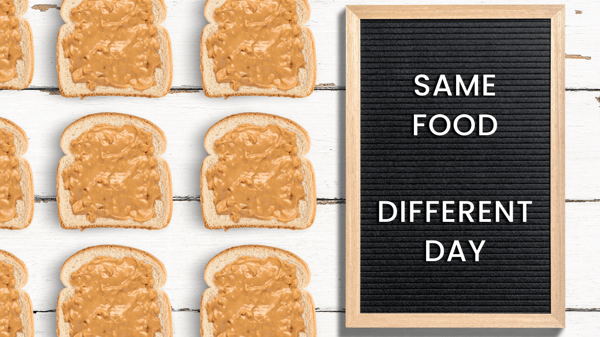 A letter board sign that says, same food different day. There are pieces of bread with peanut butter on them lined up next to the sign.