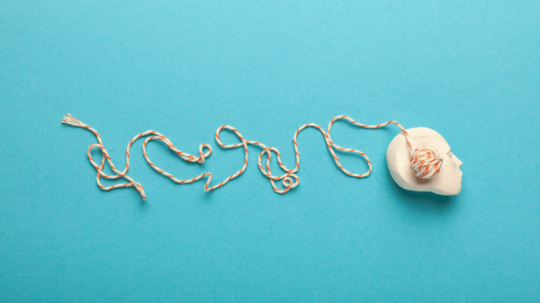 A small plastic head with a ball of yarn on it to represent a brain, while the yarn unravels behind it to represent catastrophic thoughts.