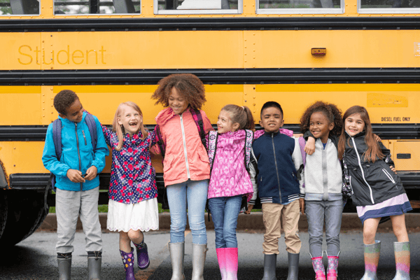 seven school-aged kids lined up in front of a school bus; some of them have ADHD, but which ones?