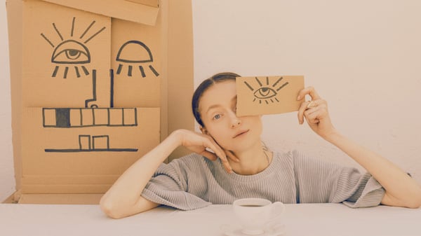 woman holding a drawing of an eye on a piece of cardboard over her actual eye