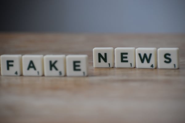 letter game pieces that are on a table and spell out "fake news"