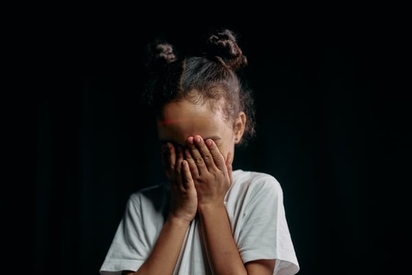 child hiding behind her hands