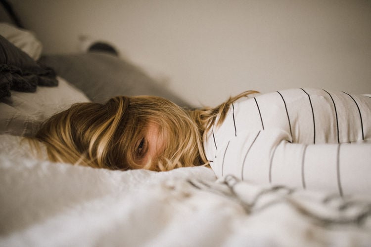 woman laying in bed with her hair mostly covering her face.