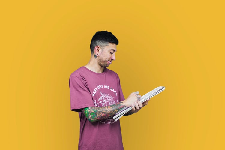 A man with tattoos holding a notebook, writing something down.