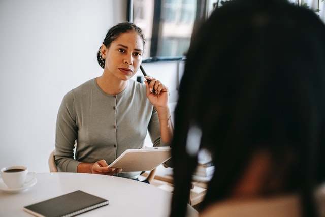 a psychologist listens to her patient closely with a clipboard in hand