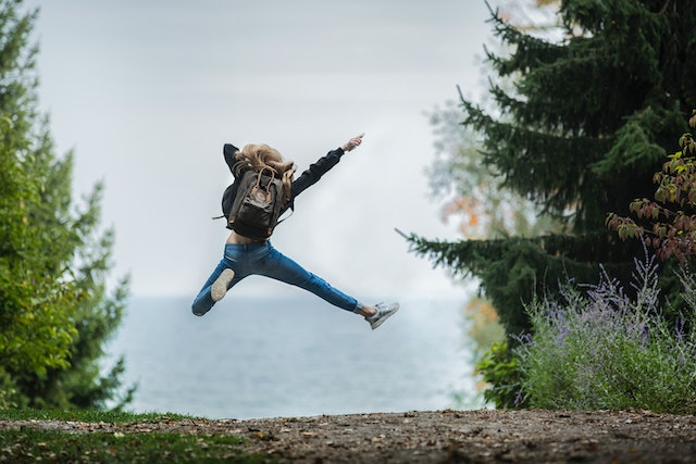 A woman with ADHD who successfully used the RAIN method to help her overcome rejection sensitive dysphoria, jumping in the air in nature