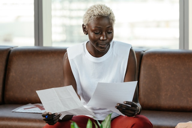 a Black woman holding two pieces of paper and comparing them