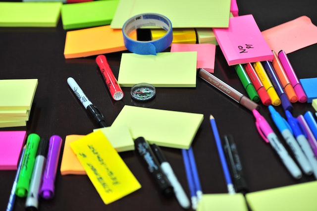 A pile of sticky notes, pens, tape, and markers to help with reminders for adhd forgetfulness