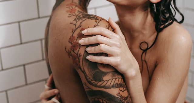 Romantic partners in the shower together. All that is visible is their hands and arms.