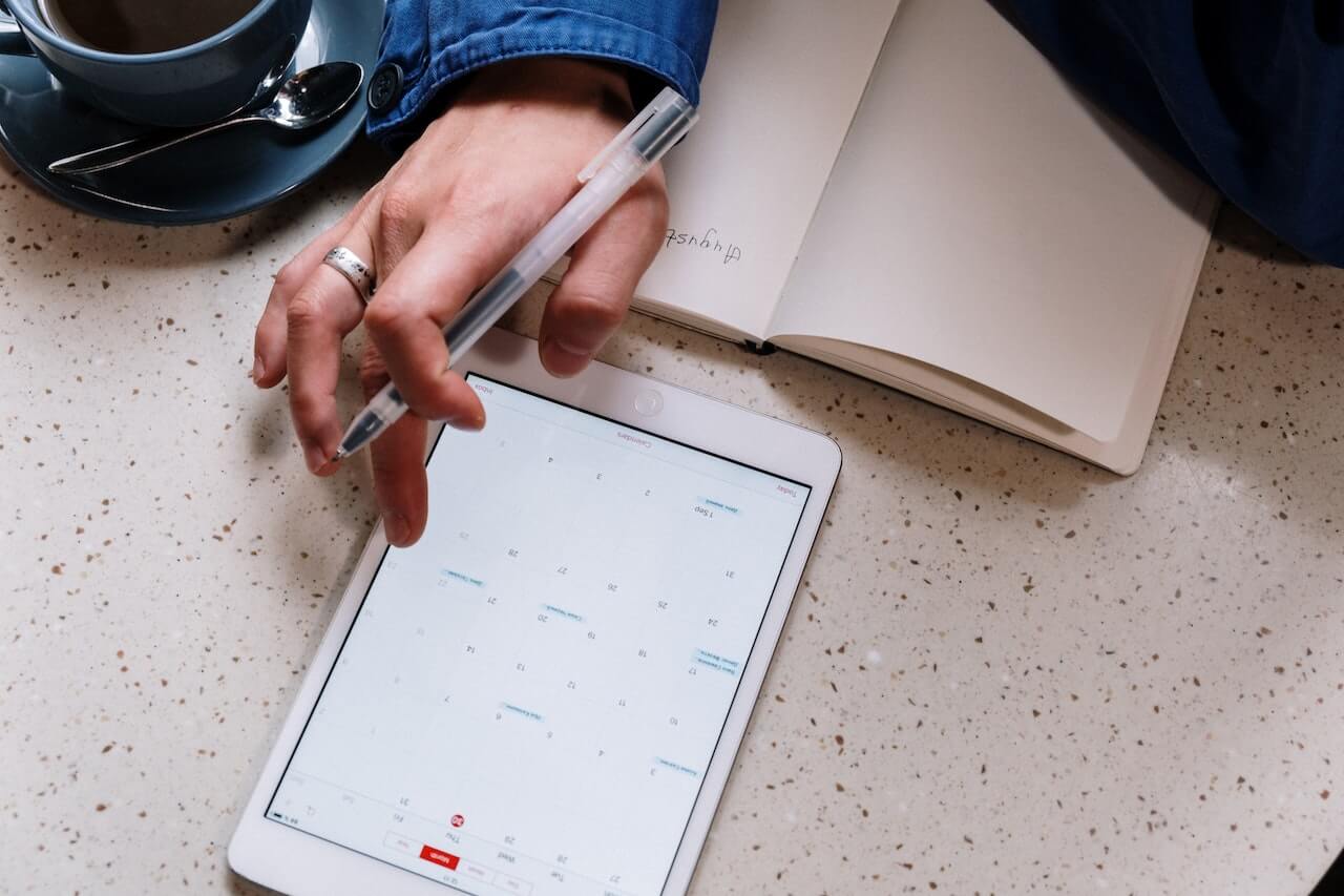 A parent with ADHD has her tablet open tot he calendar and is writing down a list of task that need to be completed tomorrow.