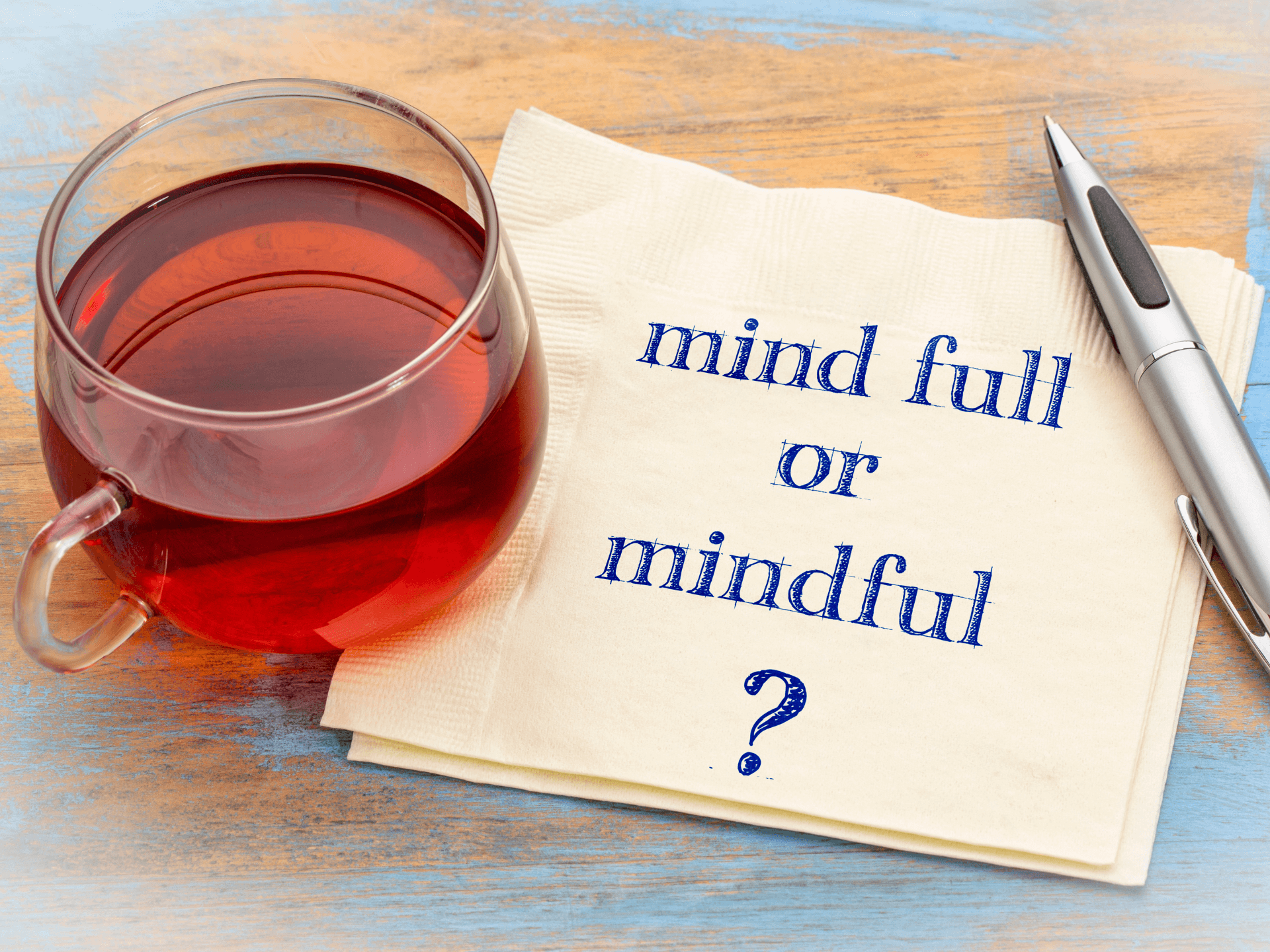 a cup of tea with a napkin next to it. the napkin has a message on it: mind full or mindful?