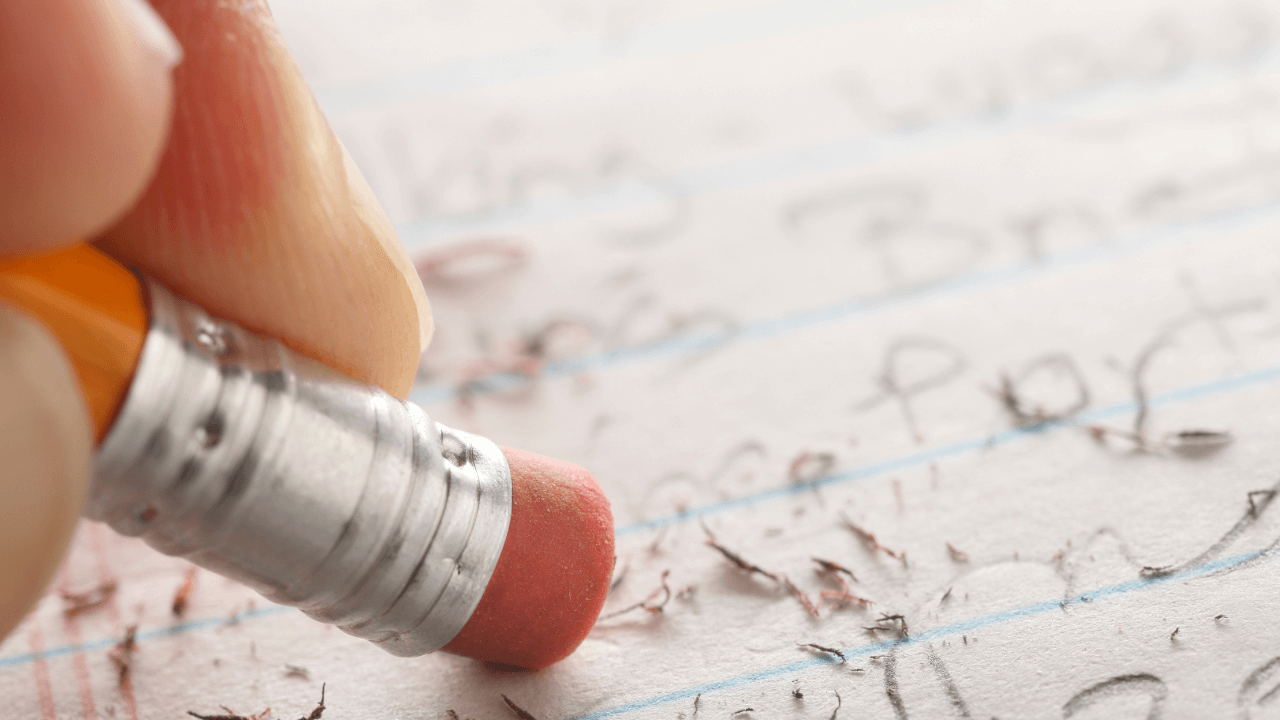 A close-up image of someone erasing something they've written on lined paper in pencil.