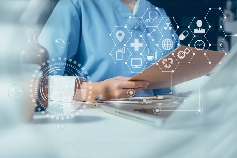 Person in blue scrubs holds a clipboard with a laptop in front of them. A transparent white overlay on top of the image shows a network with medical and technology themed icons. 