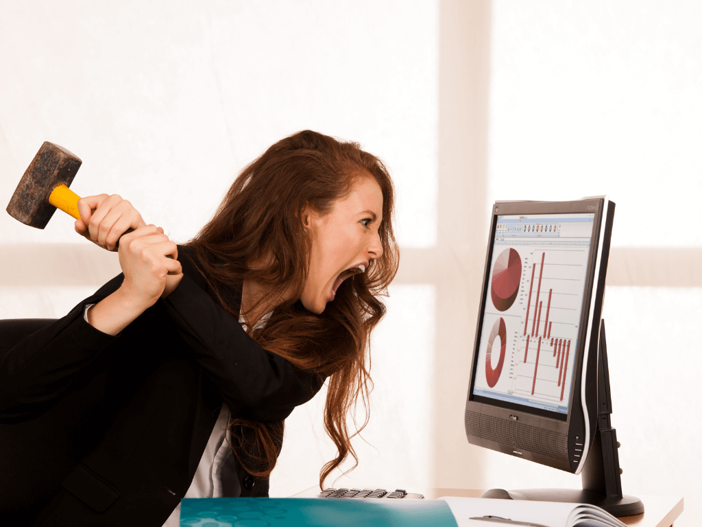 Angry woman at work taking a sledgehammer to her computer screen.