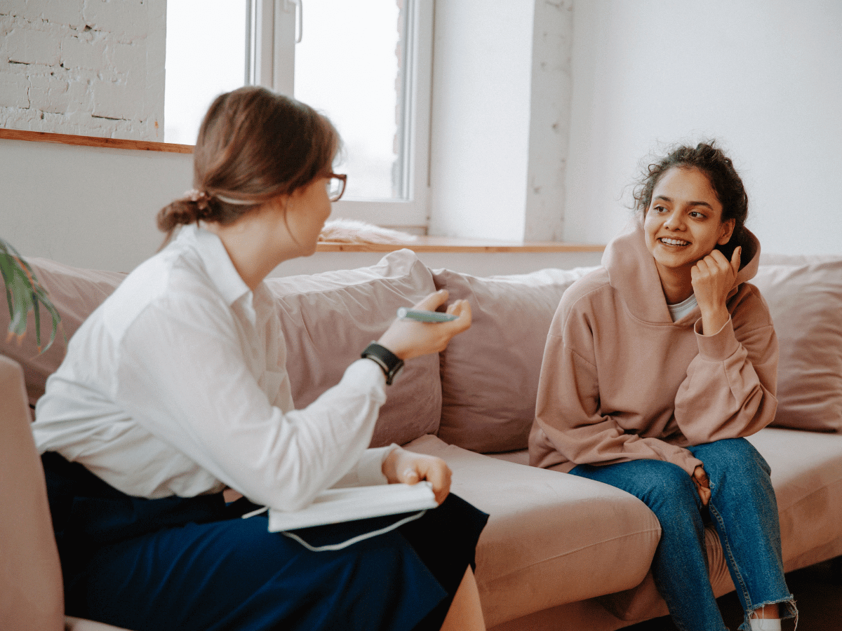 Two people engaging in a conversation on a couch, sharing ADHD advice.