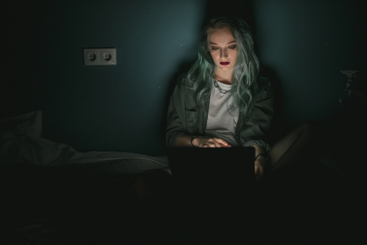 A natural night-owl with ADHD working on a laptop at nighttime. The surroundings are dark, the main light source is the laptop.