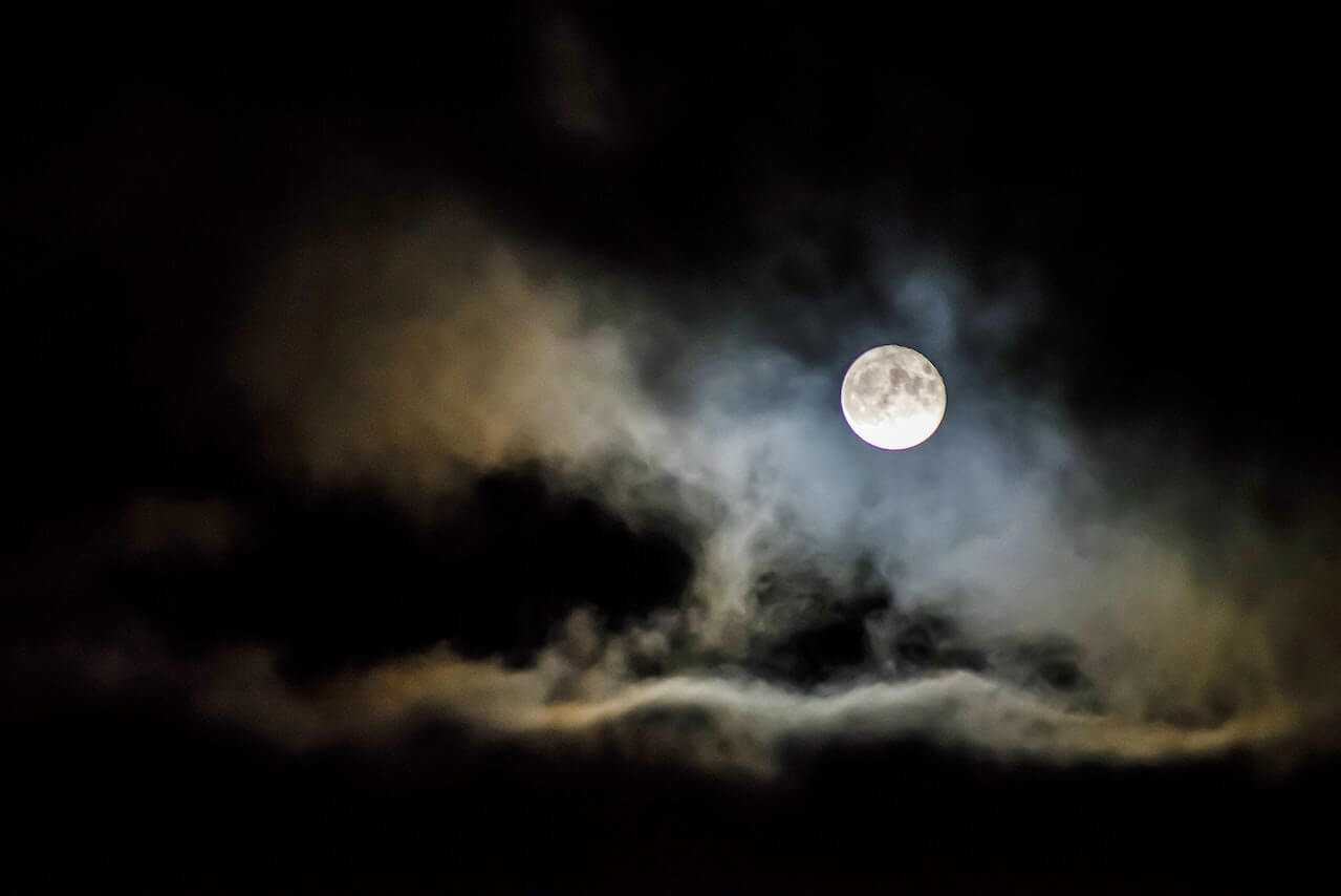 A full moon surrounded by clouds.