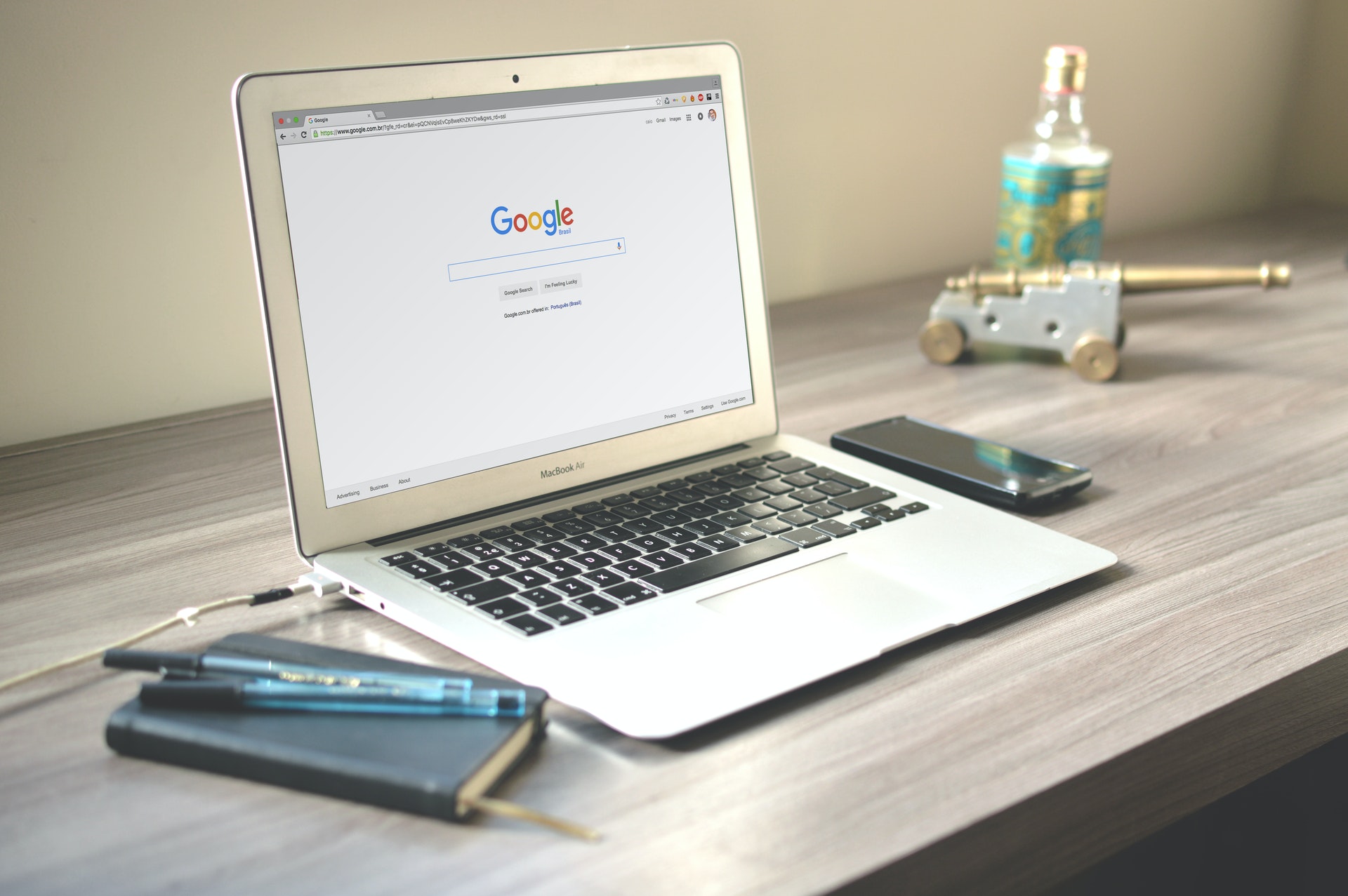an open laptop on a desk. the screen shows the google search bar.