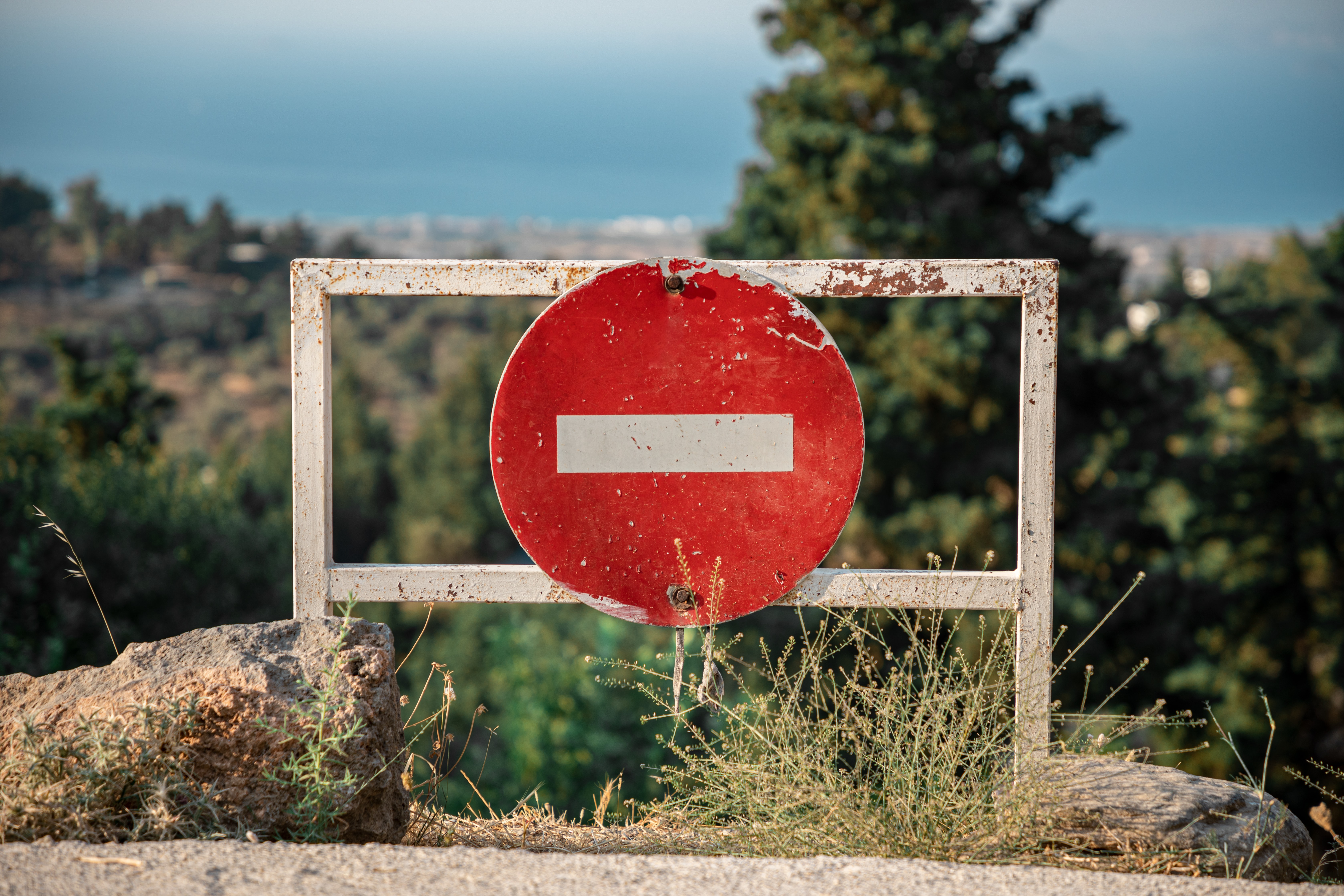 an old red forbidden sign on a rusted gate.