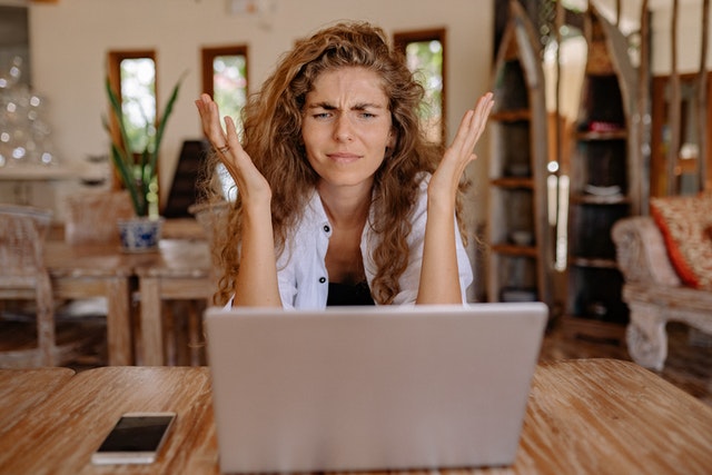 woman sitting in front of a computer, frustrated and confused