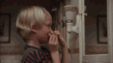 Dennis the menace playing with false teeth in the bathroom mirror. He opens the jaw, snaps it shut and a few teeth fall into the sink and down the drain, his eyes widened in surprise - oops!
